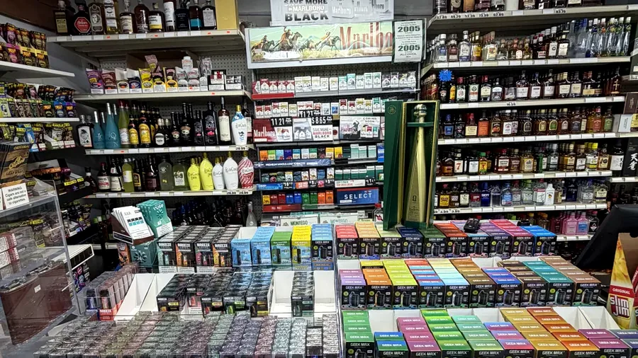 Wide real adult product counter with vape and tobacco displays inside Harrison Liquor