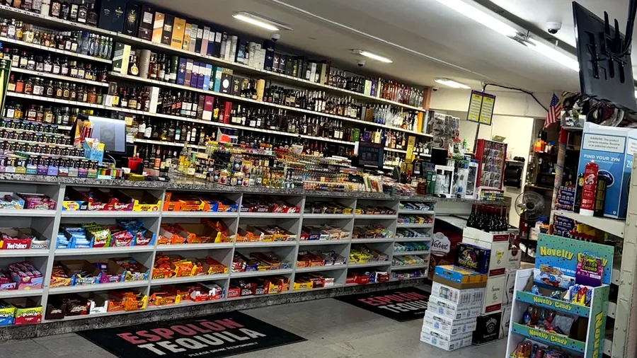 Wide interior view of snacks, drinks and store shelves inside Harrison Liquor